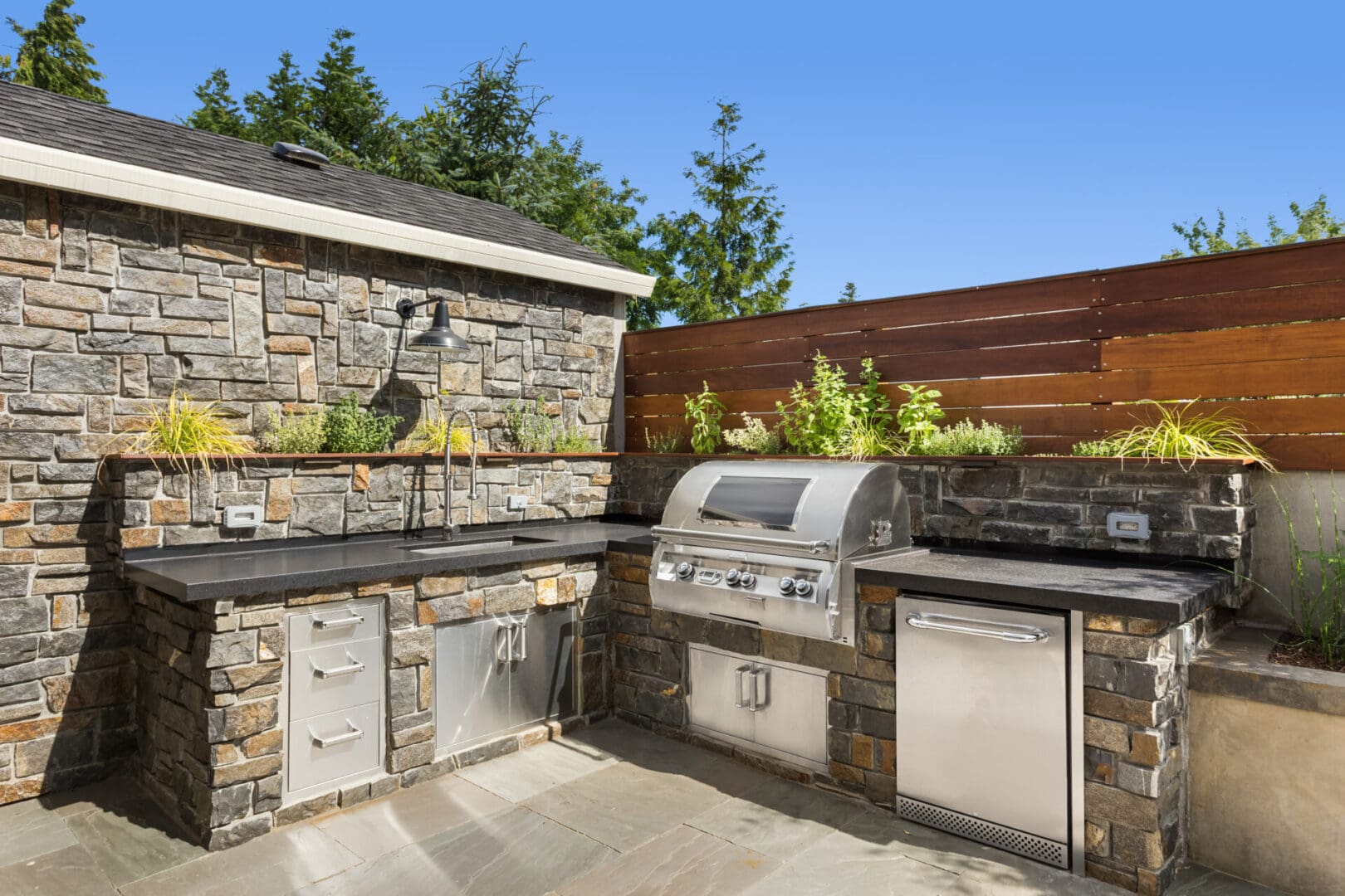 A stone outdoor kitchen with an oven and sink.