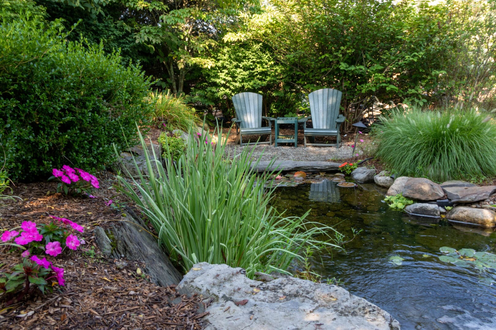 A pond with two chairs sitting next to it.