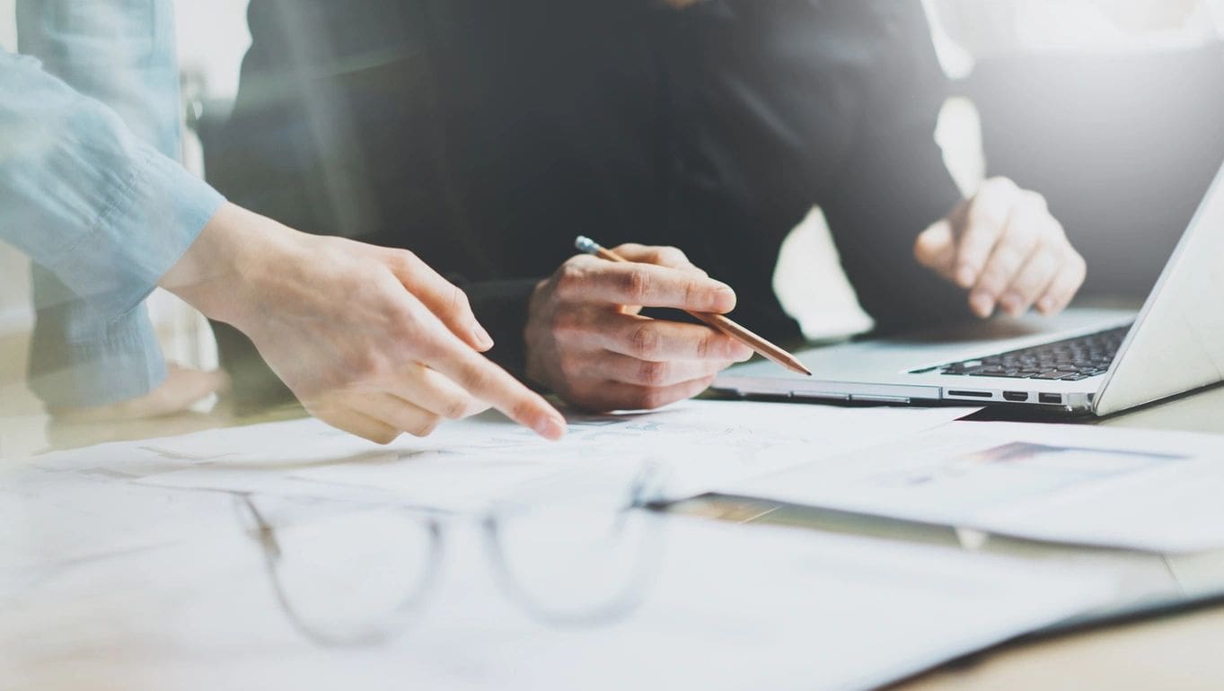 Two people are sitting at a table with papers.